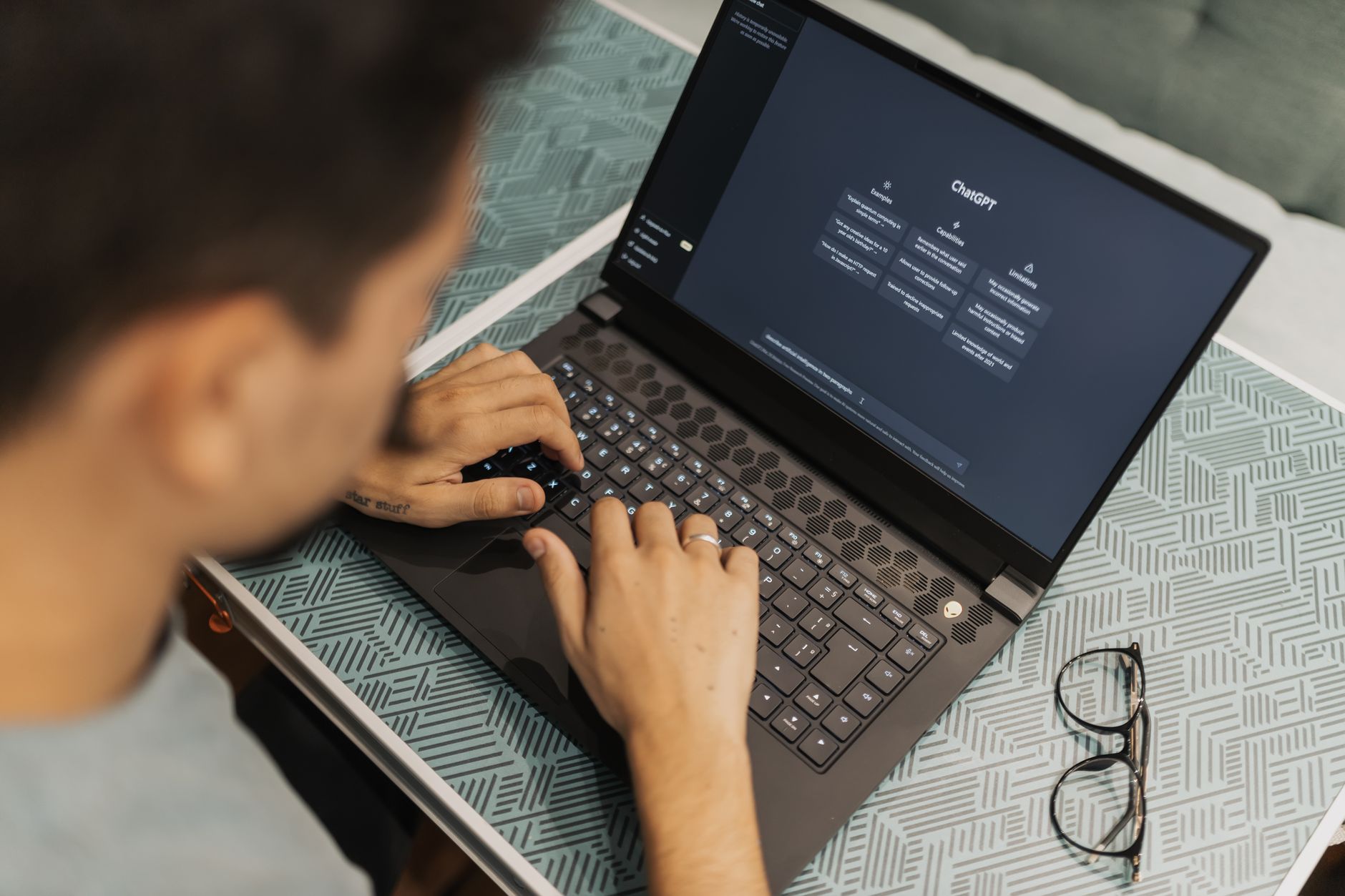 A teacher using a laptop to plan a lesson with an AI chatbot visible on the screen