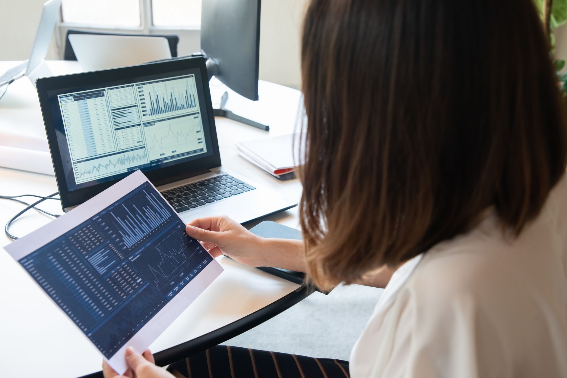a financial advisor reviewing client portfolio charts on a laptop screen in a bright modern office