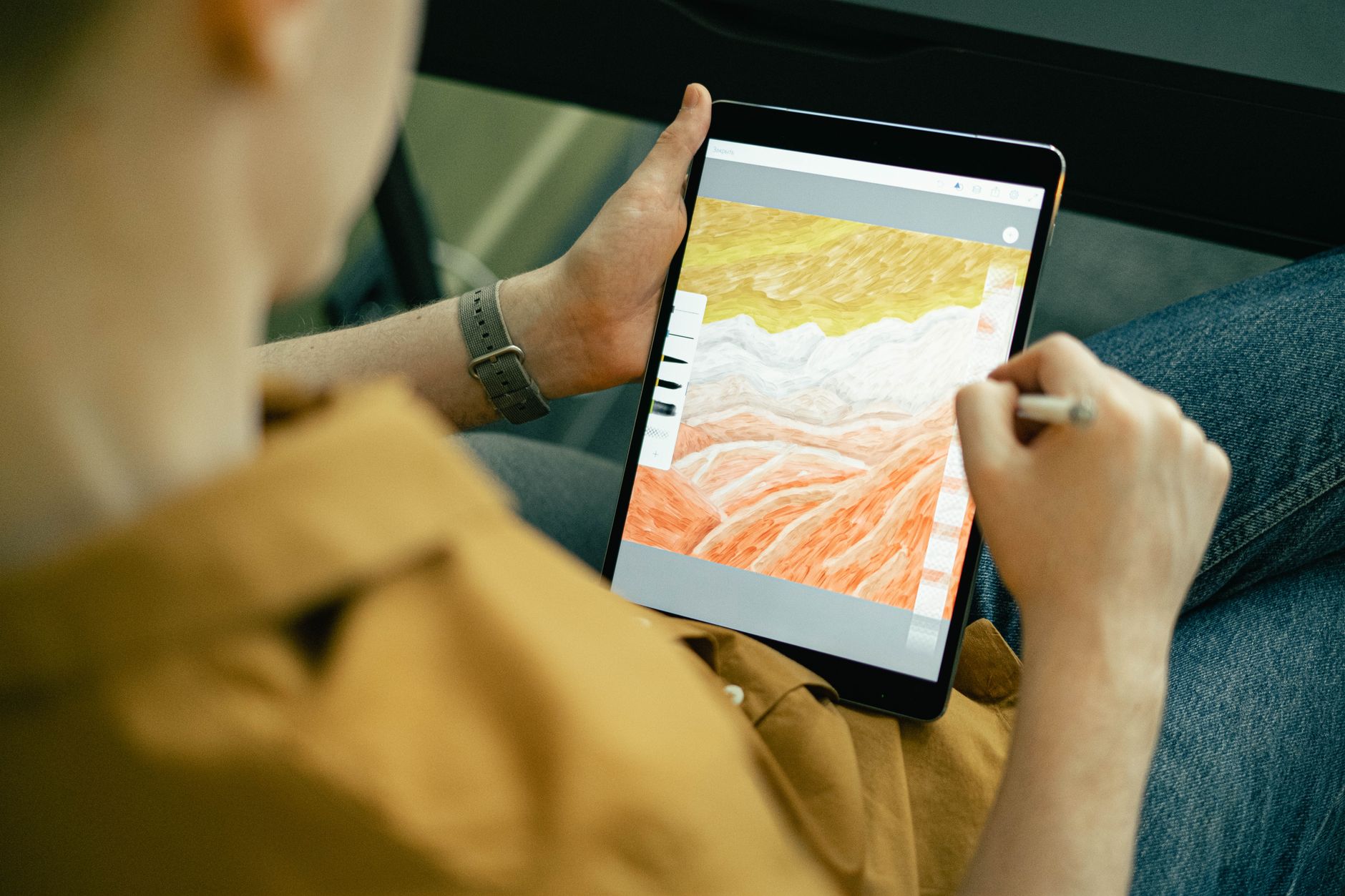 a graphic designer using a stylus on a tablet with colorful digital artwork on the screen